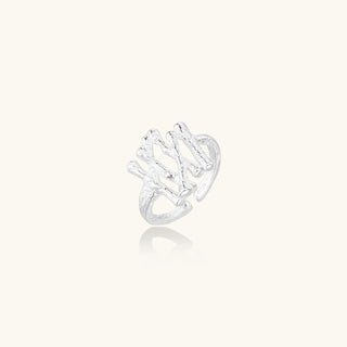 Sculptural sterling silver ring with organic branch design and textured surfaces on cream background