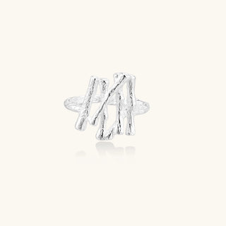 Sculptural sterling silver ring with organic branch design and textured surfaces on cream background
