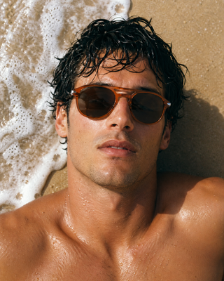 Cossino Luxury Orange Navigator sunglasses worn by a male model on a luxurious beach
