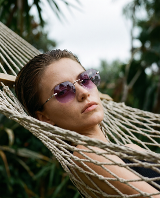 Woman wearing sunglasses and lying in a hammock with a blurred natural background